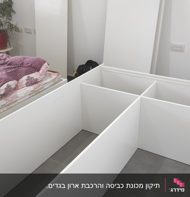 חלקי ארון לבן בהרכבה על רצפה אפורה